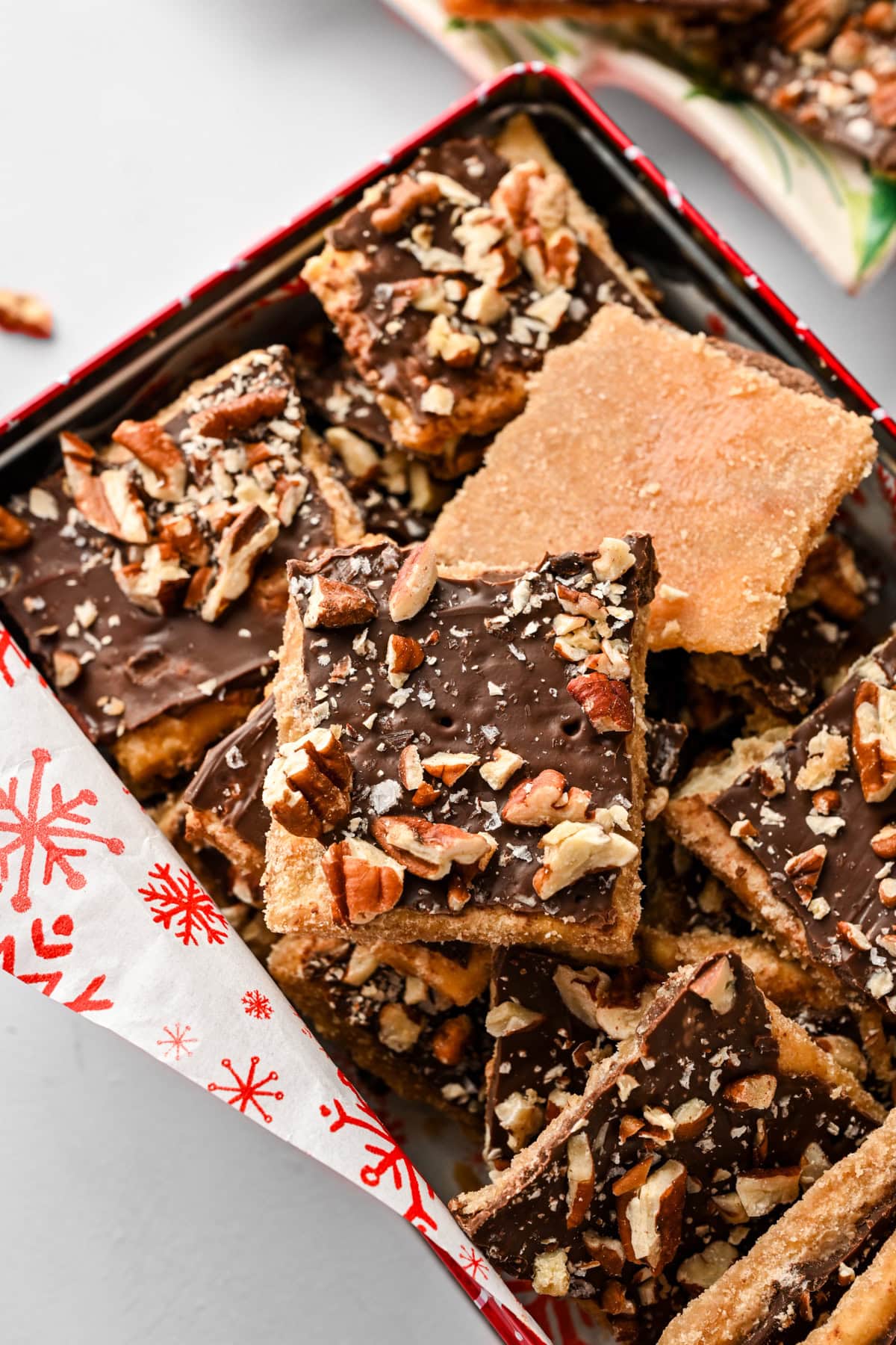 Close up side view of bourbon pecan christmas crack in a cookie tin.