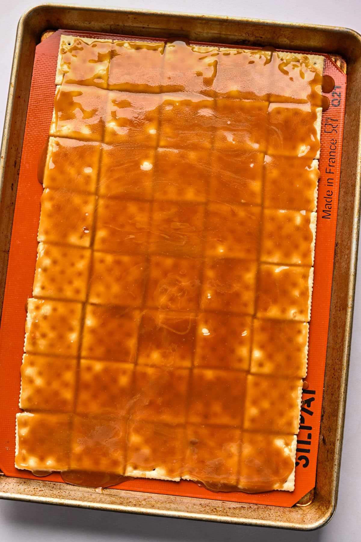 Bourbon caramel poured onto saltine crackers on a sheet pan.