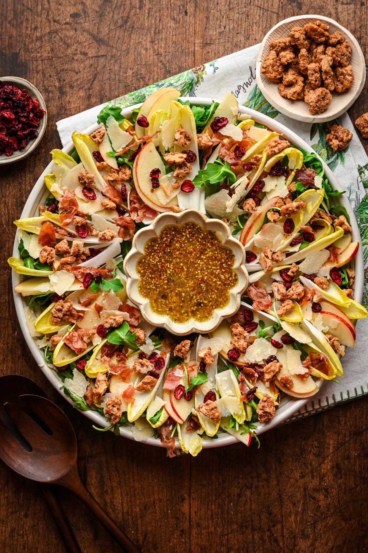 Christmas wreath salad on a platter with bowl of vinaigrette in the middle.