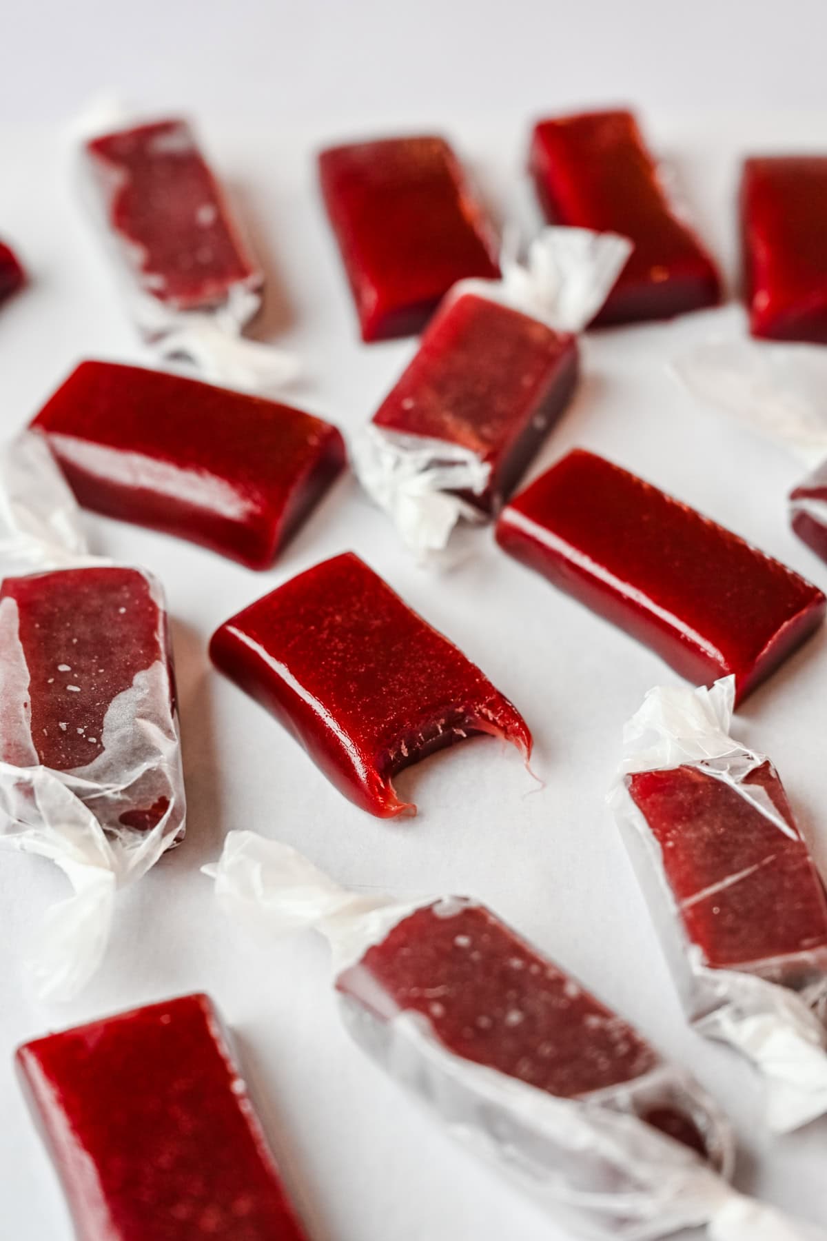 Close up view of a pomegranate caramel with a bite taken out of it.