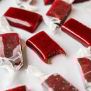 Close up view of a pomegranate caramel with a bite taken out of it.