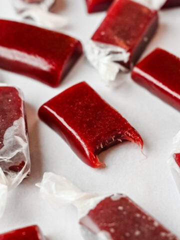 Close up view of a pomegranate caramel with a bite taken out of it.