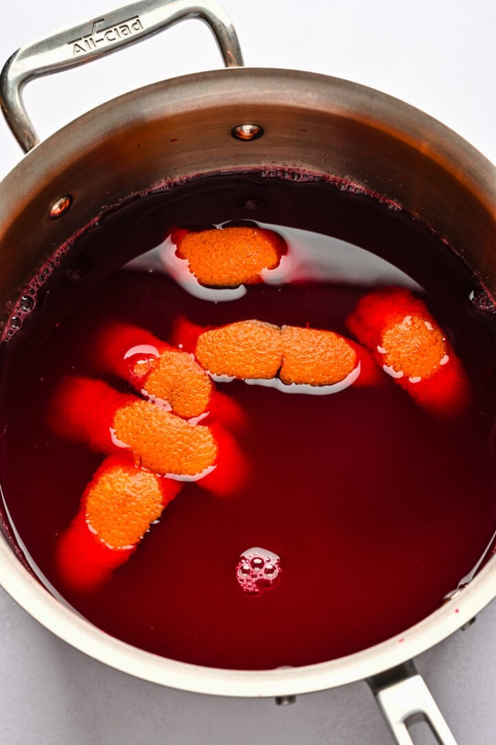 Juice with orange peels floating in a pot.