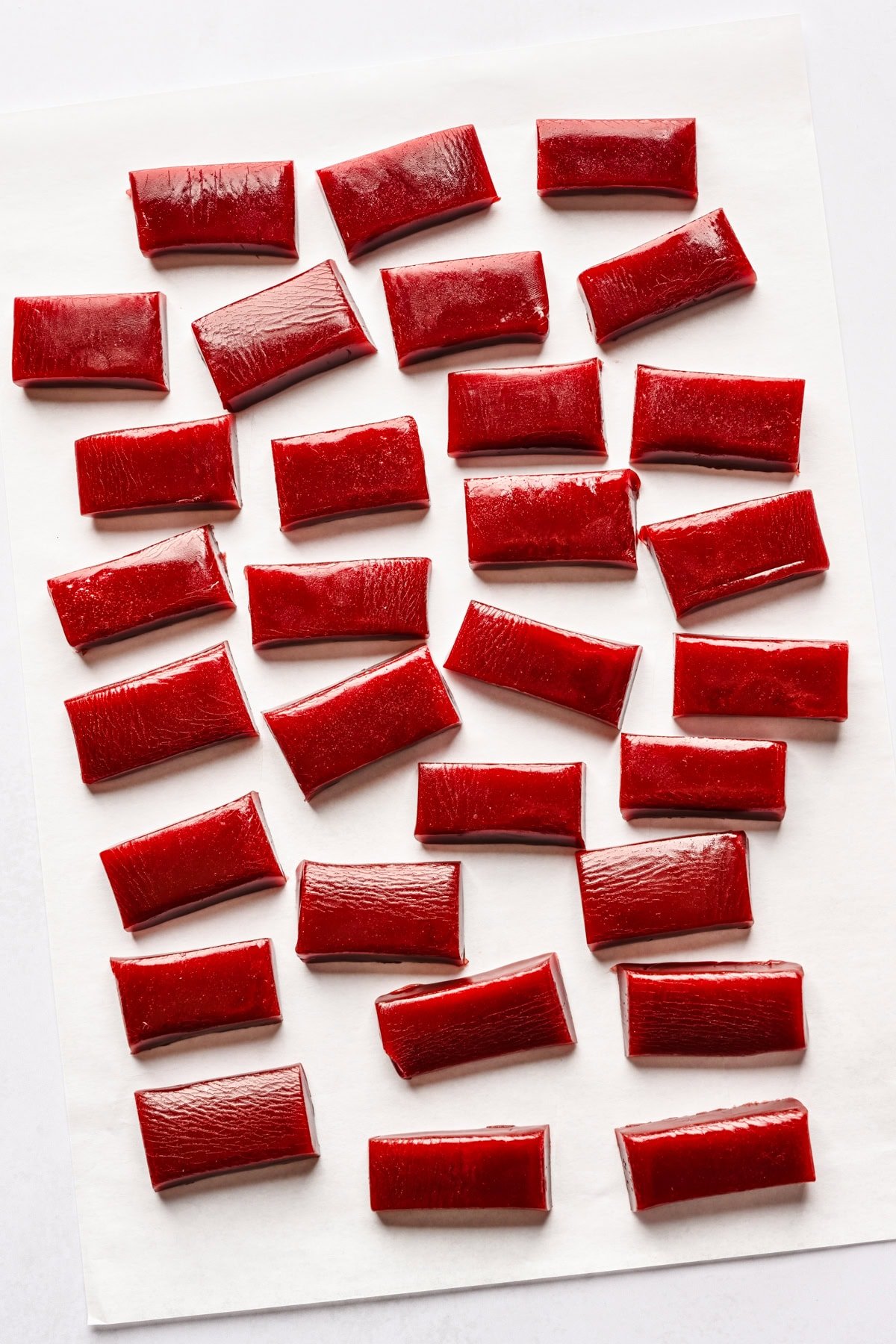 Pomegranate caramels cut up on a sheet of parchment paper.