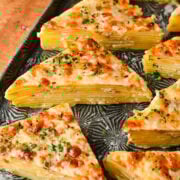 Delicious layered potato gratin wedges with melted cheese and parsley. Perfect comfort food for family dinners.