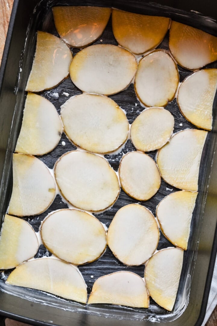 First layer of potatoes put down in a roasting pan.