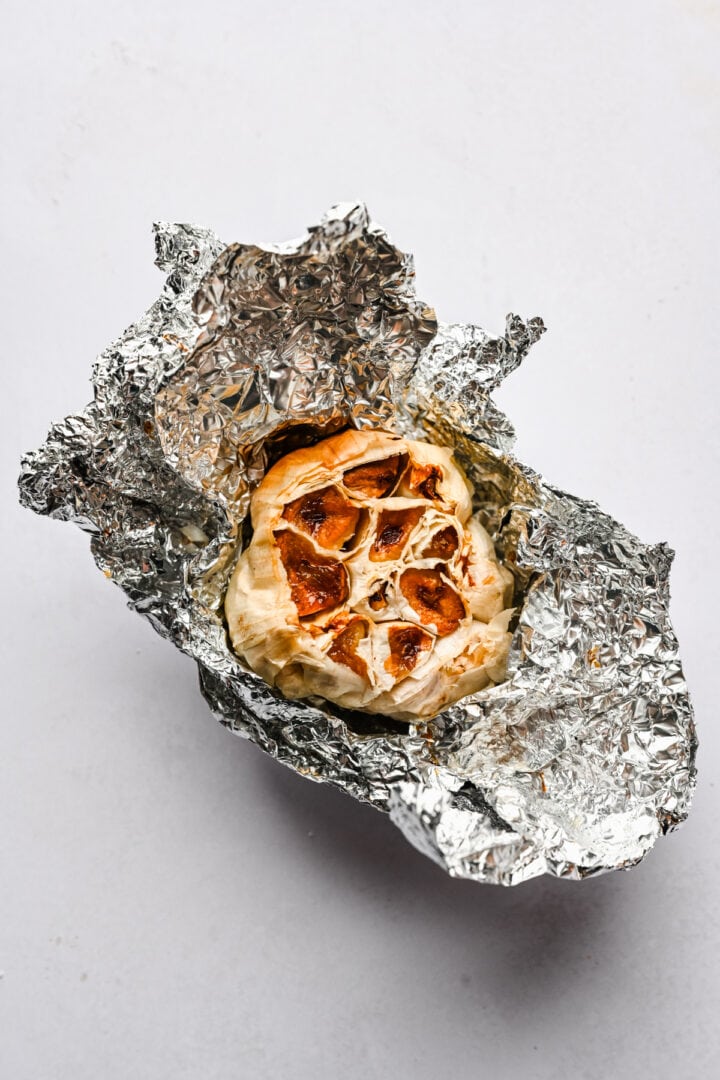 head of garlic in aluminum foil after roasting.