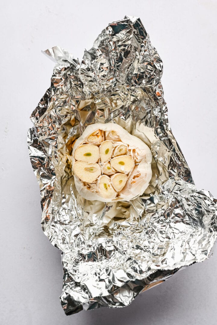 head of garlic in aluminum foil before roasting.