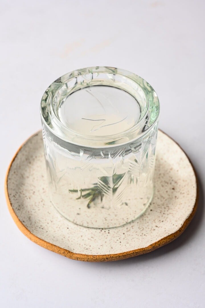 cocktail glass covering a piece of smoking rosemary.