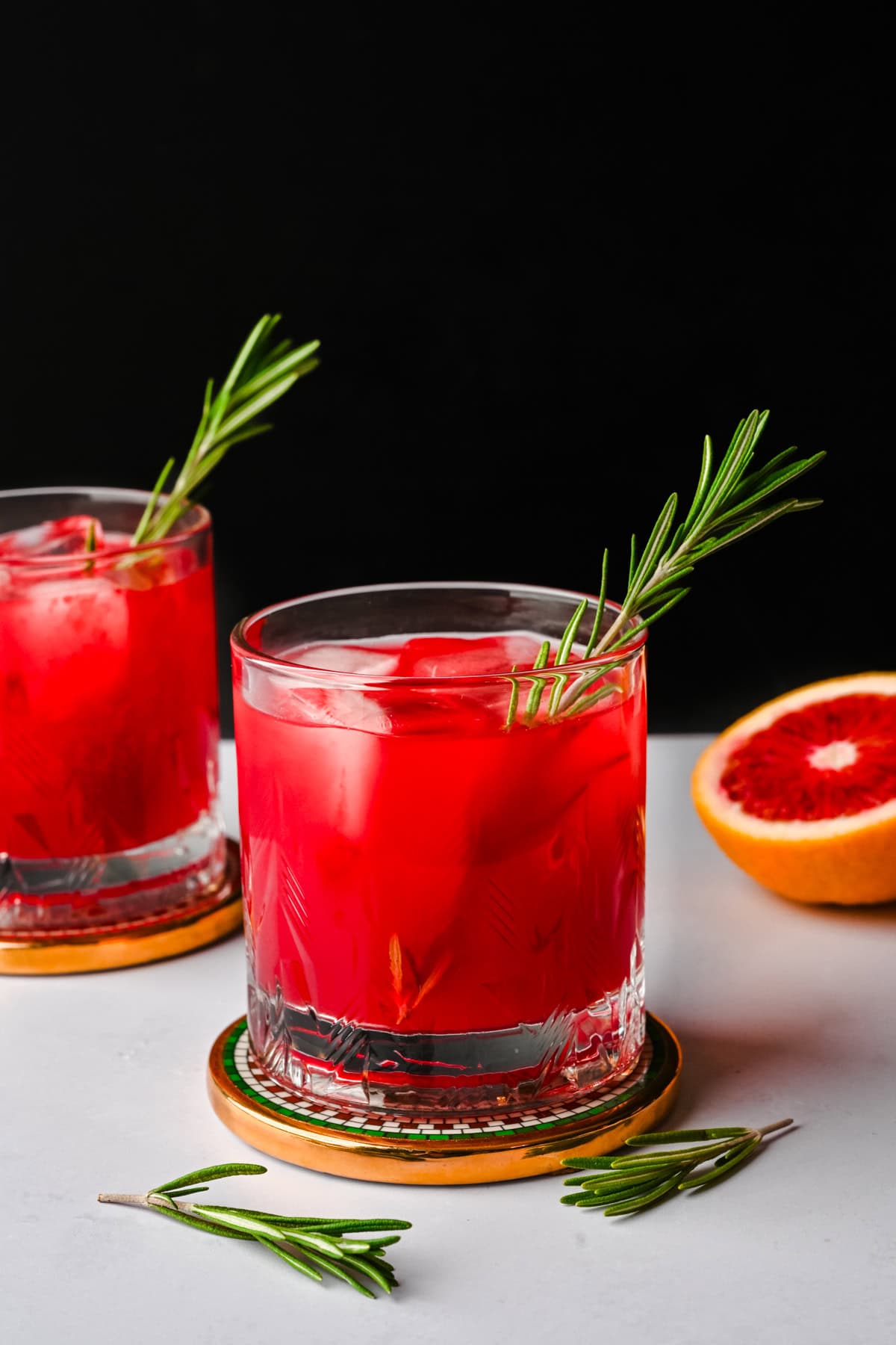 Side view of blood orange fireside cocktail garnished with a rosemary sprig. 
