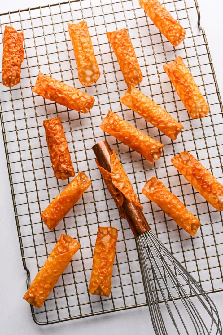 using a whisk handle to roll florentine cookies into cannoli shells.