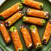Crispy cheese-filled jalapeño poppers with green onions and chocolate chips on a green plate.