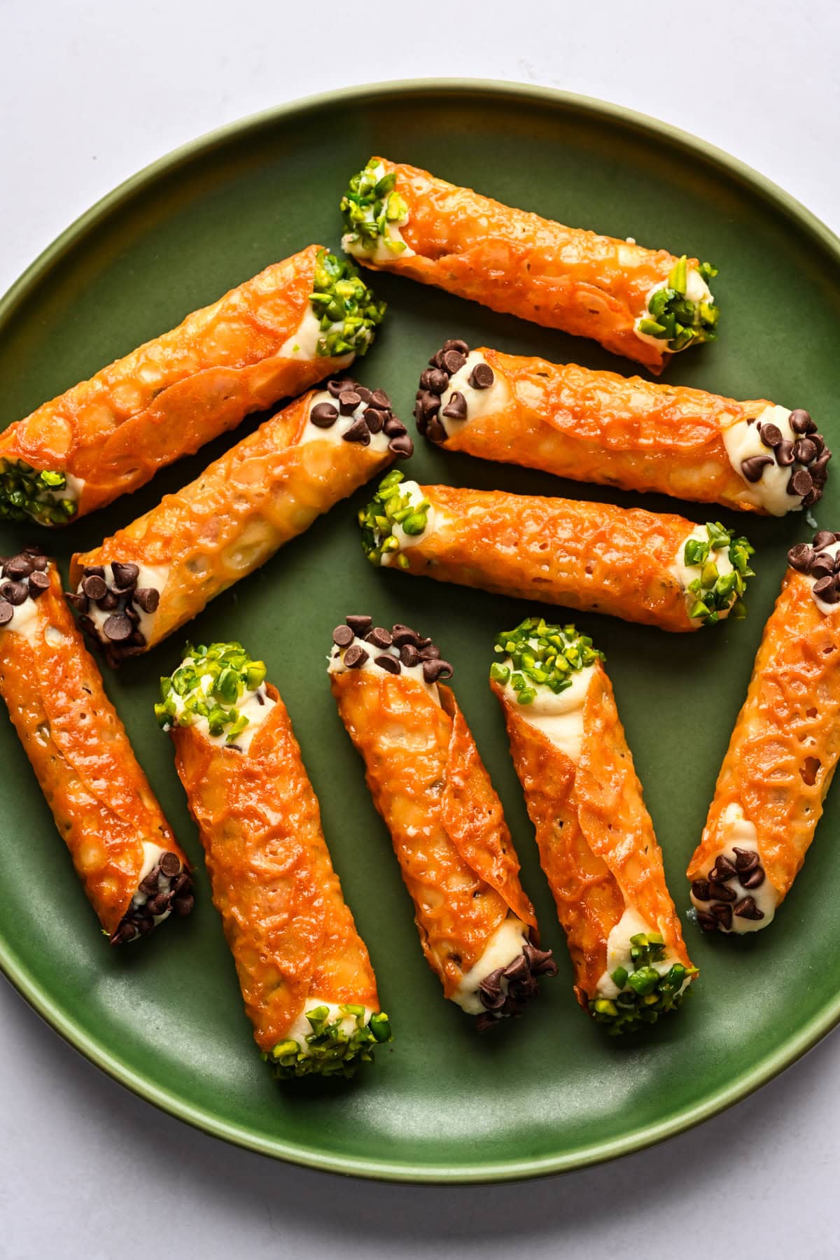 Overhead view of cannoli made with a florentine cookie, garnished with mini chocolate chips and pistachios.