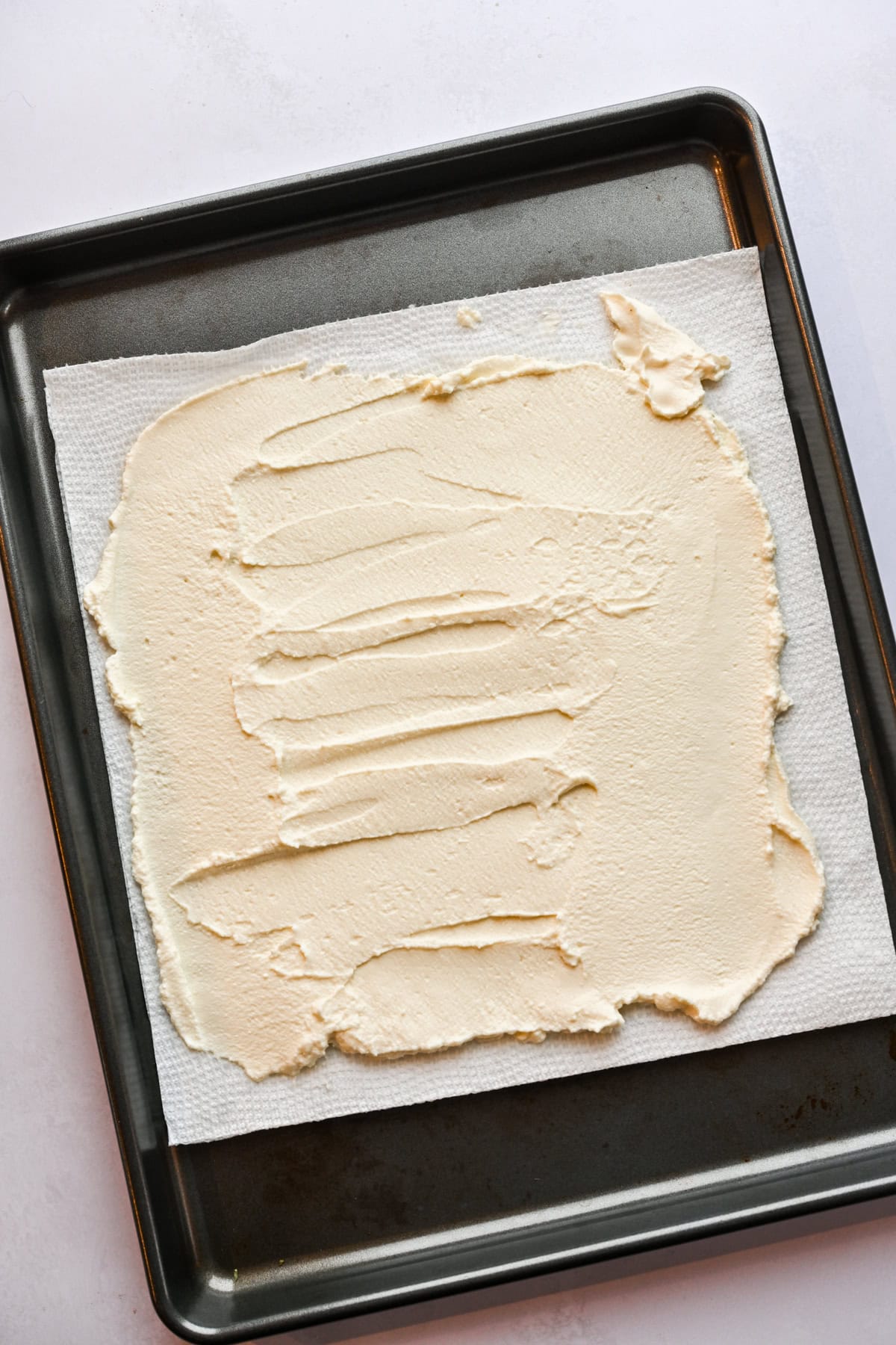 Ricotta spread out on paper towel to drain.