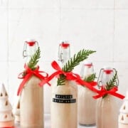 Baileys Irish Cream bottles decorated for the holidays with red ribbons and green sprigs, perfect for Christmas gatherings.