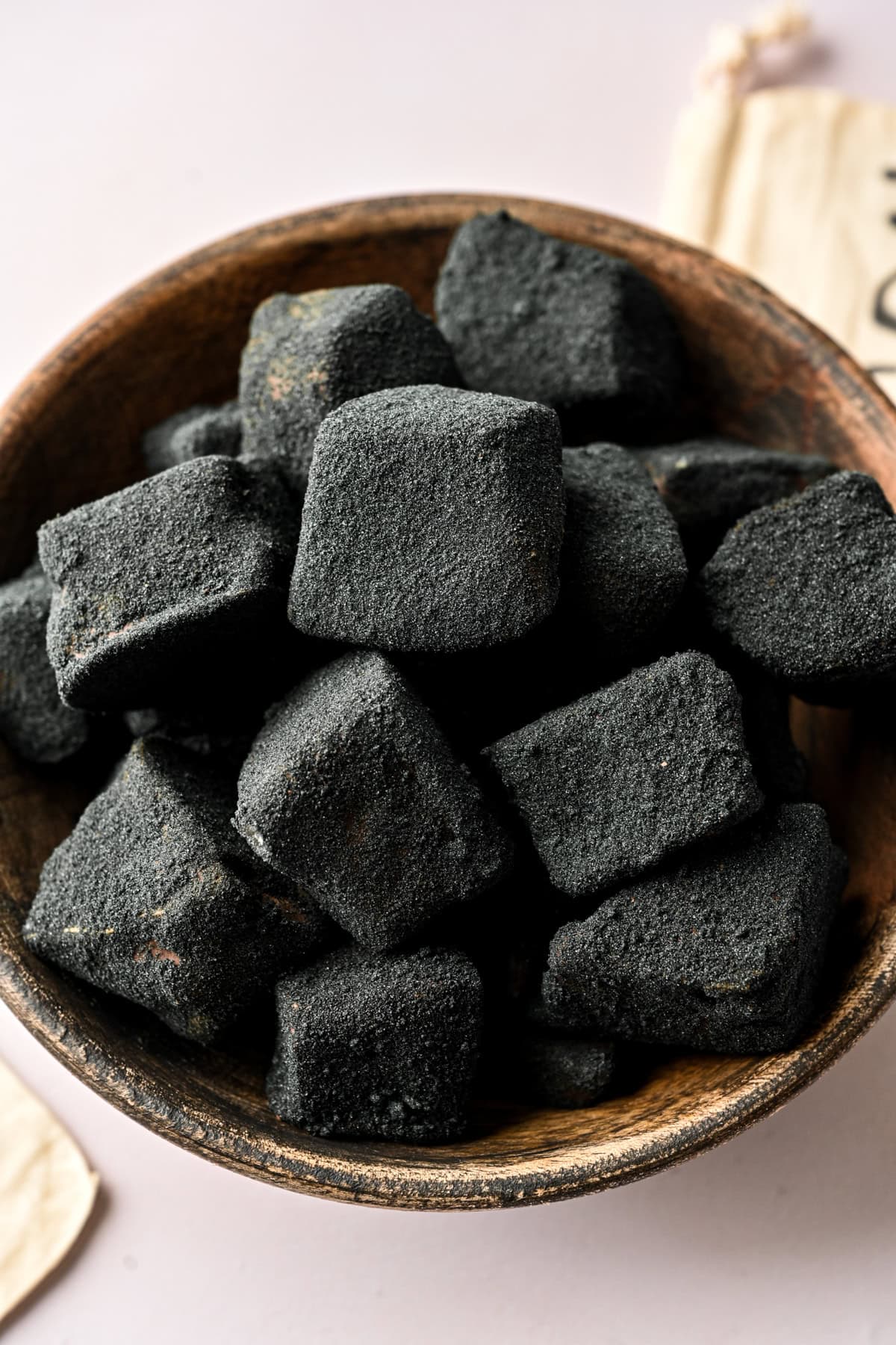 45 degree angle view of edible coal candy in a bowl.