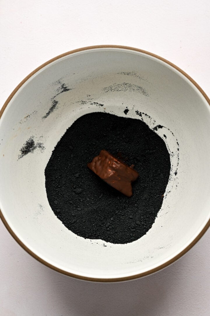 Overhead view of piece of chocolate covered honeycomb in black sugar. 
