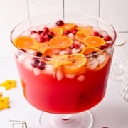 Side view of jingle juice christmas punch garnished with orange slices, cranberries and star fruit.
