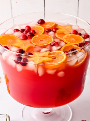 Side view of jingle juice christmas punch garnished with orange slices, cranberries and star fruit.