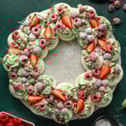 Fresh berry wreath cake with strawberries, raspberries, and powdered sugar garnish.