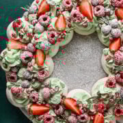 Fresh berry-topped pavlova cake with whipped cream and mint, ideal for summer dessert recipes.