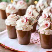 Peppermint Espresso martini pudding shots with whipped cream and christmas tree in background.