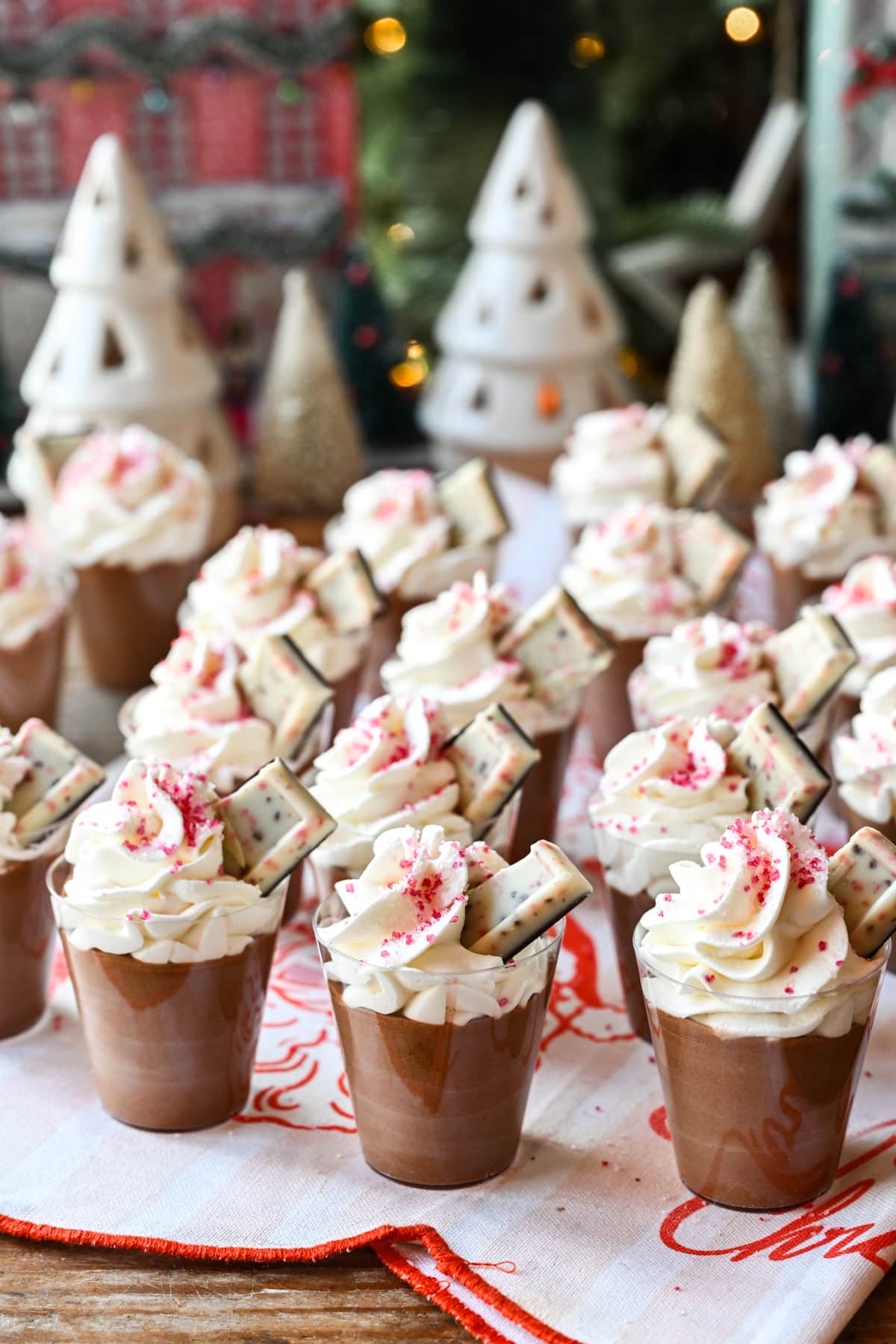 Peppermint Espresso martini pudding shots with whipped cream and christmas tree in background.