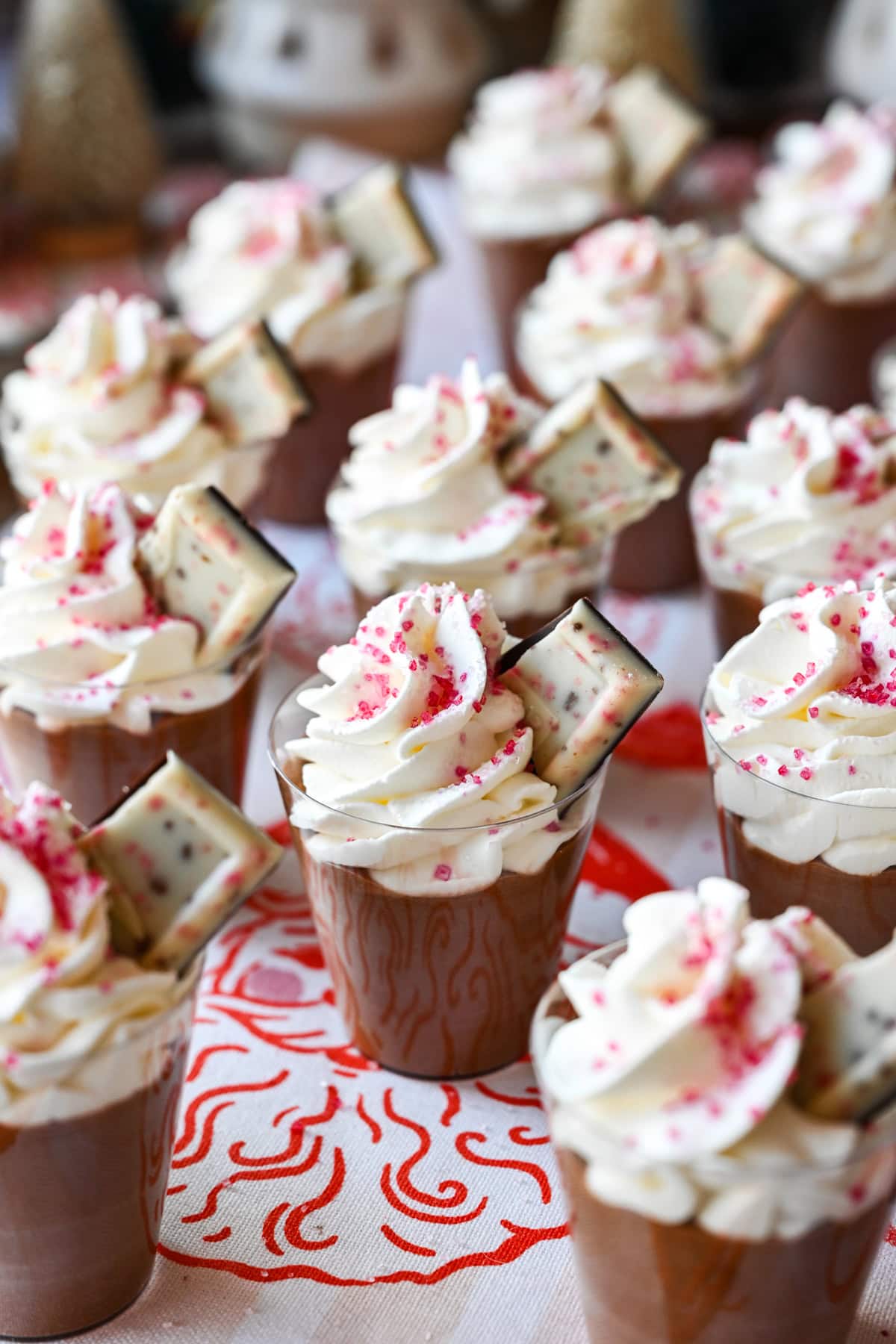 Peppermint Espresso martini pudding shots with whipped cream and christmas tree in background.
