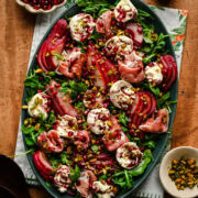 Overhead view of salad with burrata, prosciutto and poached pears on a platter.