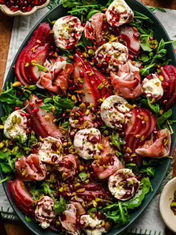 Overhead view of salad with burrata, prosciutto and poached pears on a platter.