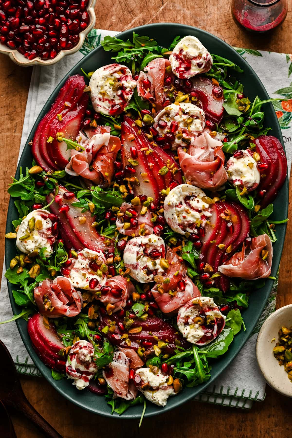 Overhead view of salad with burrata, prosciutto and poached pears on a platter.