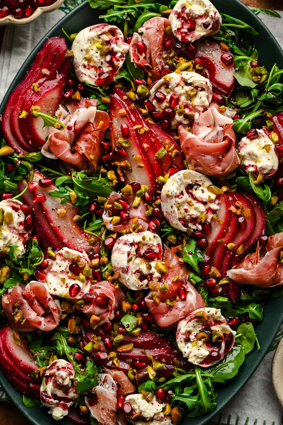 Overhead view of salad with burrata, prosciutto and poached pears on a platter.