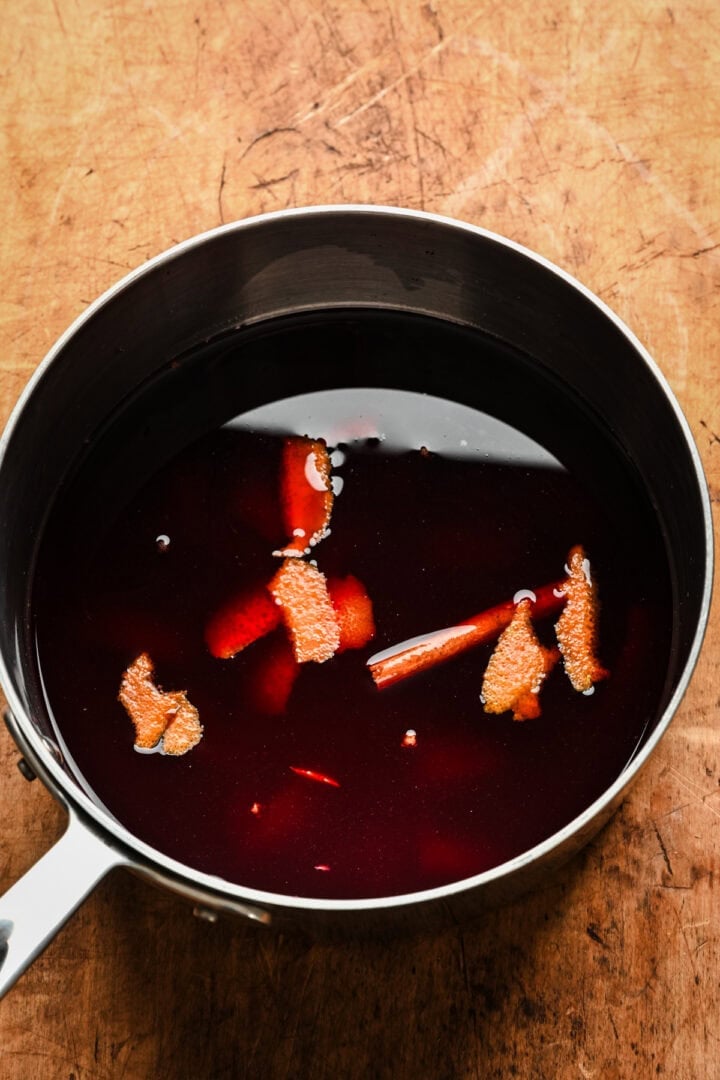 Red wine poaching ingredients in a pot before adding pears. 