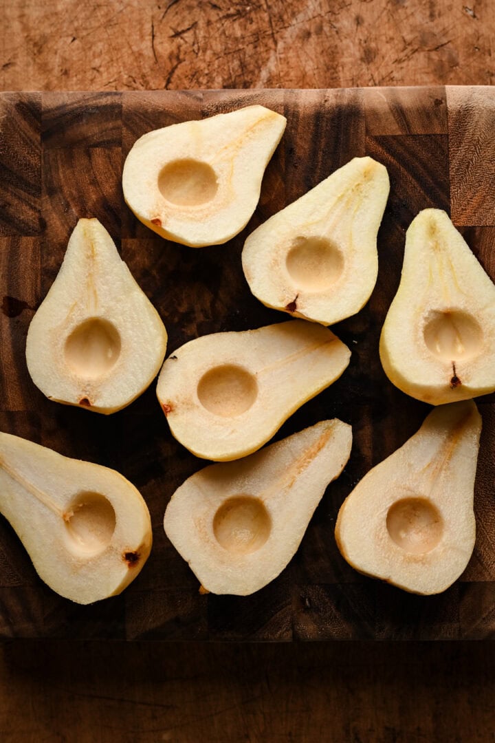 Pears peeled and halved on a cutting board. 