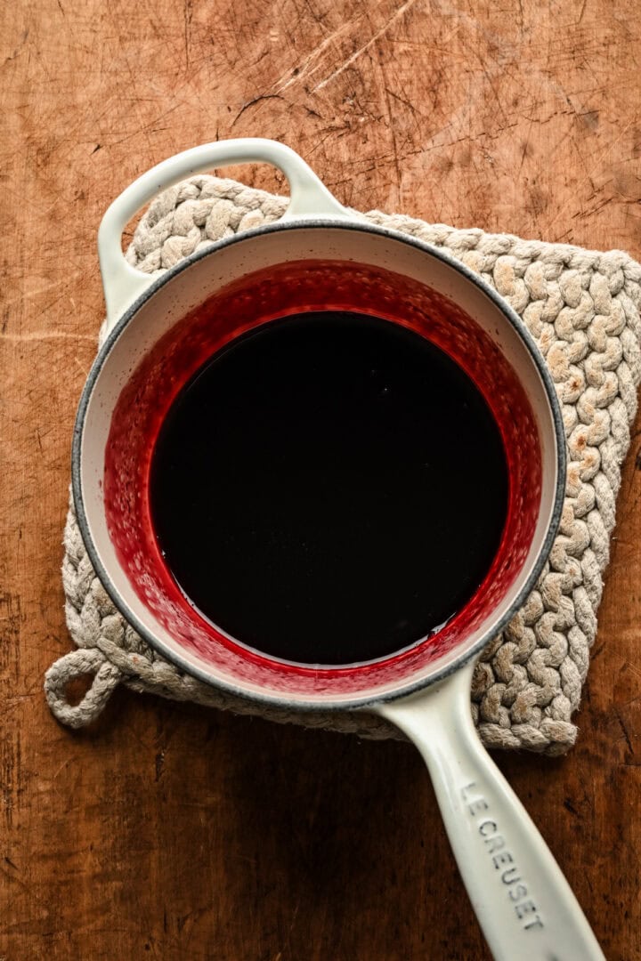 Overhead view of red wine poaching liquid in pot. 