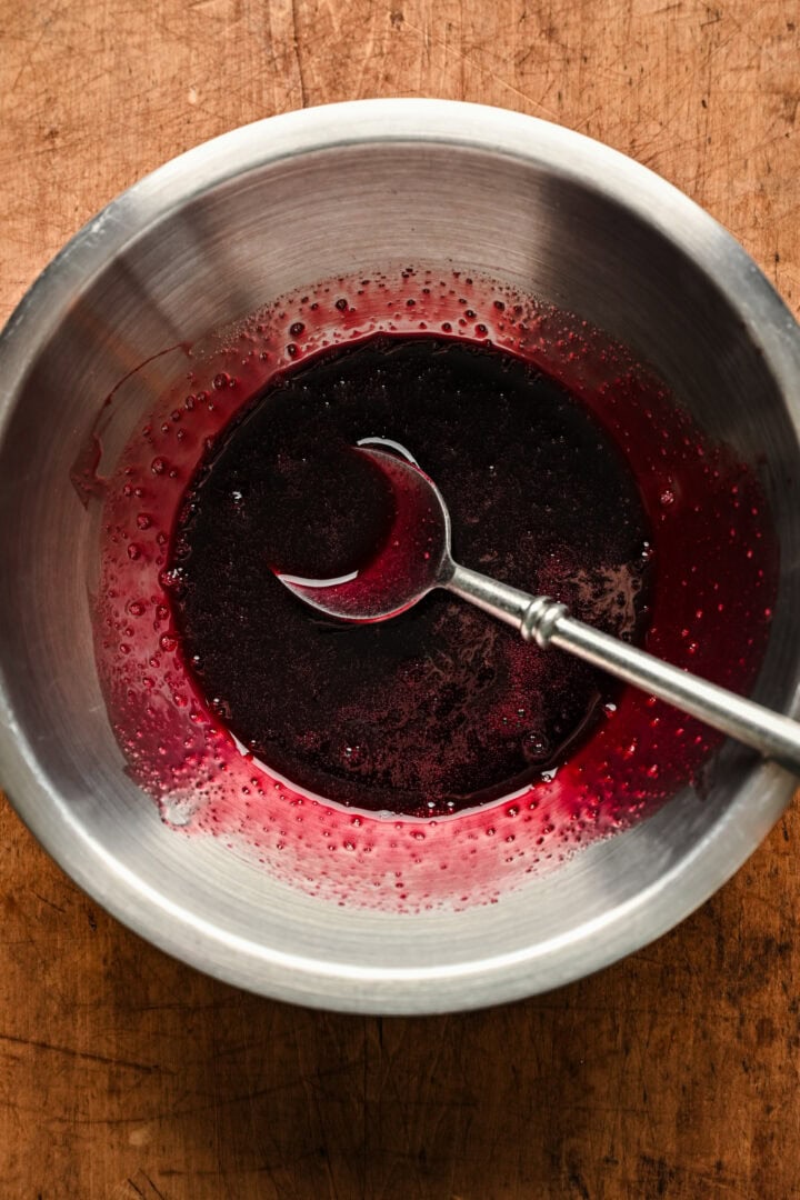 Overhead view of reduced red wine poaching liquid in bowl.
