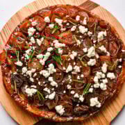 Slow cooker mushroom pizza with feta and herbs on a wooden pizza peel.