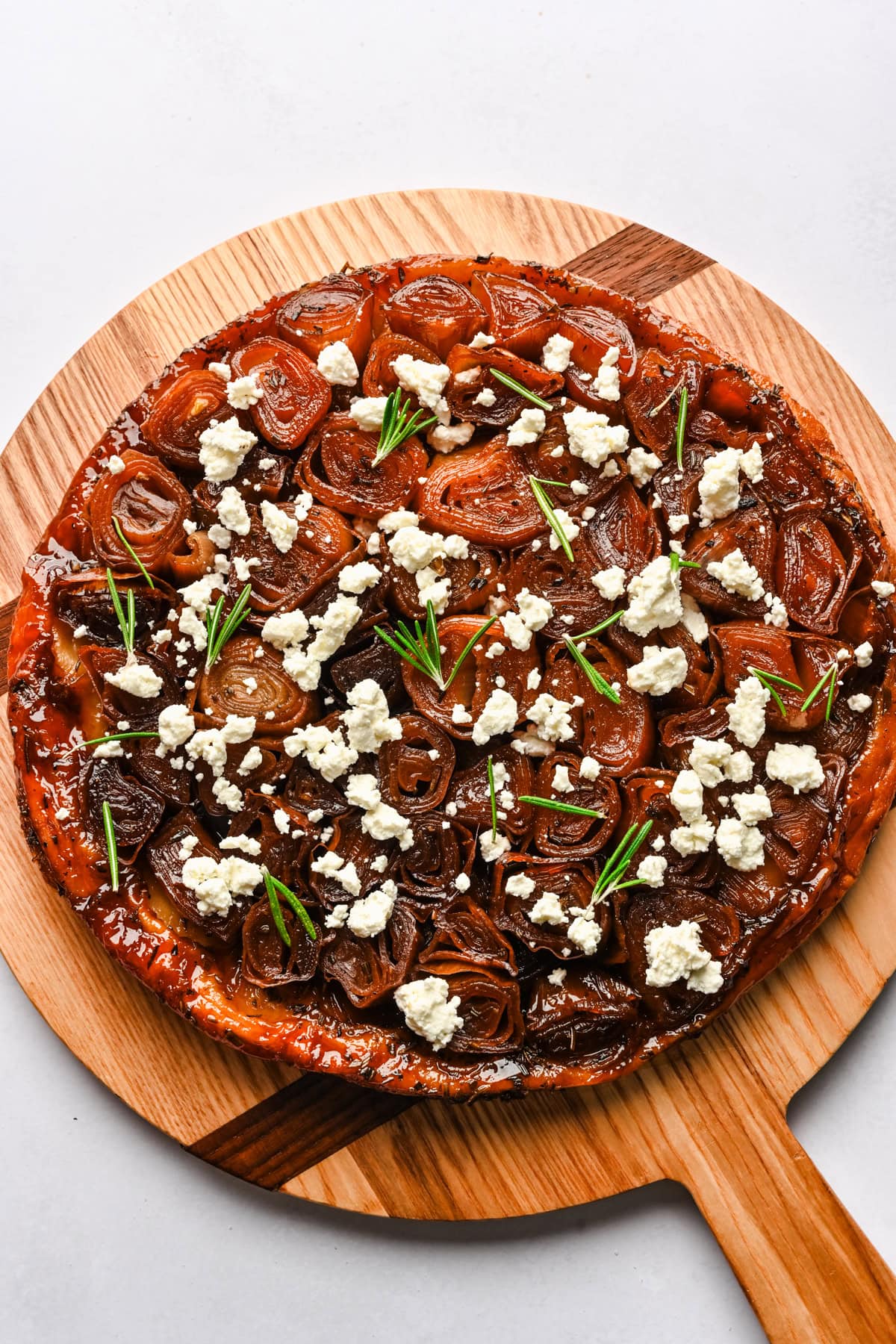 Overhead view of onion tarte tatin topped with goat cheese and rosemary.