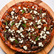 Overhead view of onion tarte tatin topped with goat cheese and rosemary.