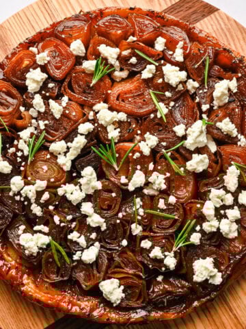 Overhead view of onion tarte tatin topped with goat cheese and rosemary.