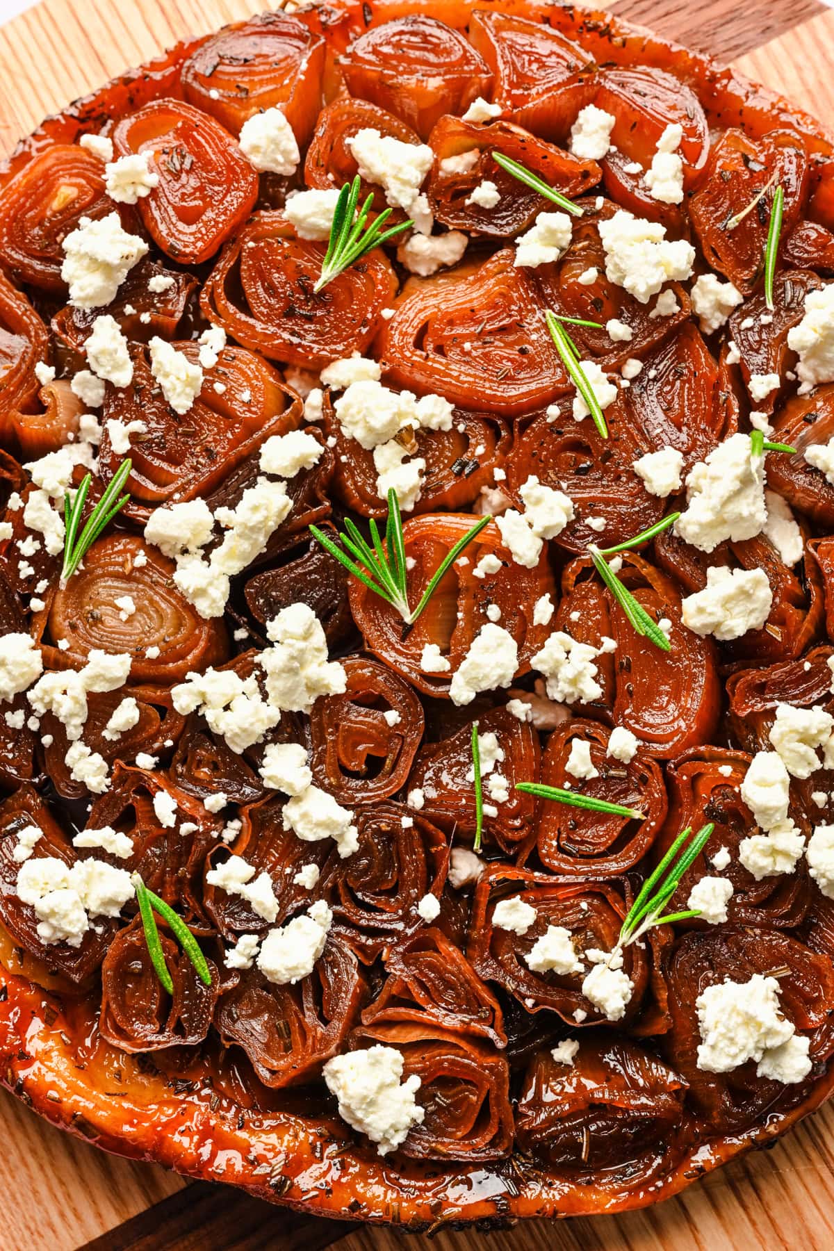 Overhead view of onion tarte tatin topped with goat cheese and rosemary.
