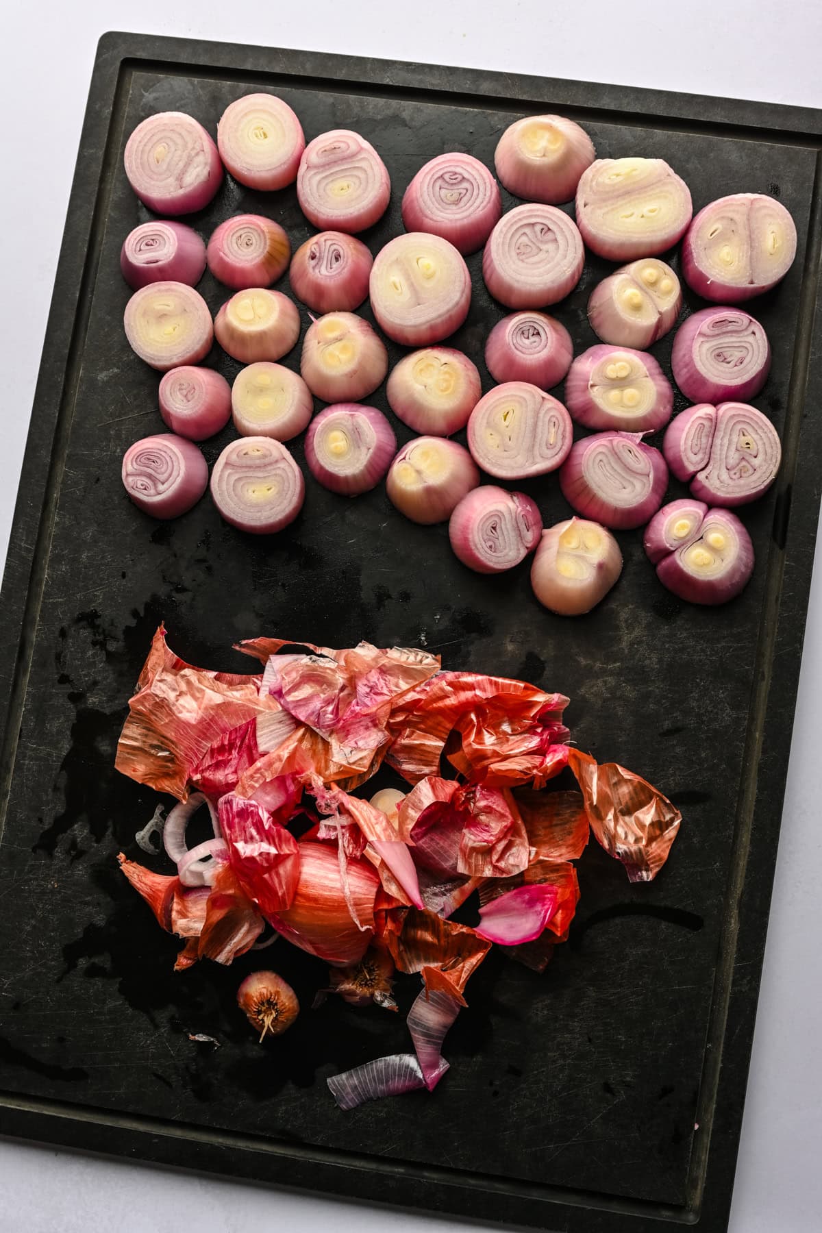 shallots sliced into rounds on a cutting board next to skins.