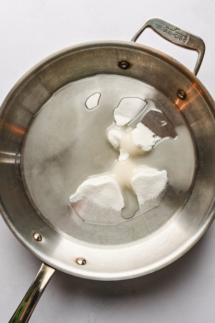 Sugar and water in a skillet before dissolving.