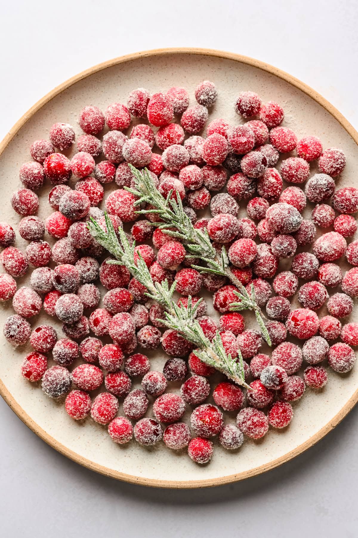 Sugared cranberries and rosemary on a plate.