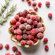 Frozen cranberries in a bowl with some scattered around, perfect for holiday recipes.
