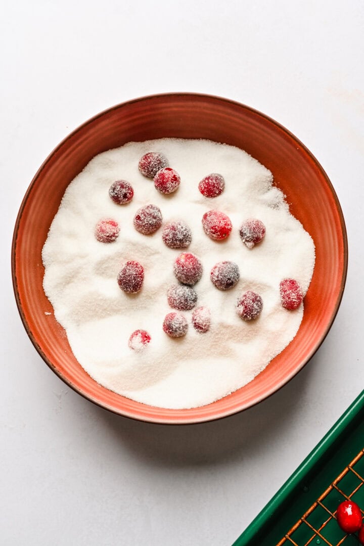 Sugared cranberries in a bowl of sugar.