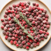 Sugared cranberries and rosemary on a plate.