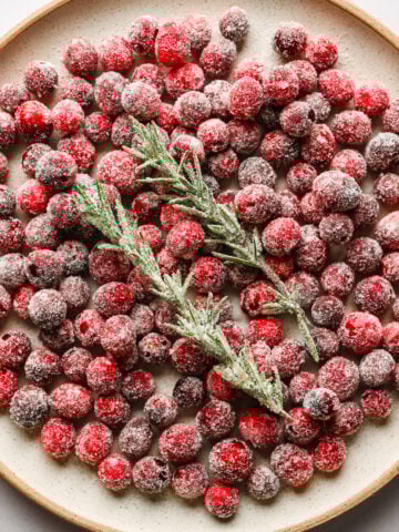Sugared cranberries and rosemary on a plate.