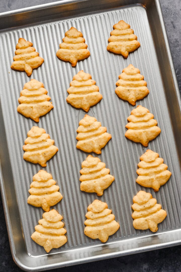 White cheddar spritz crackers in tree shape on cookie sheet after baking.