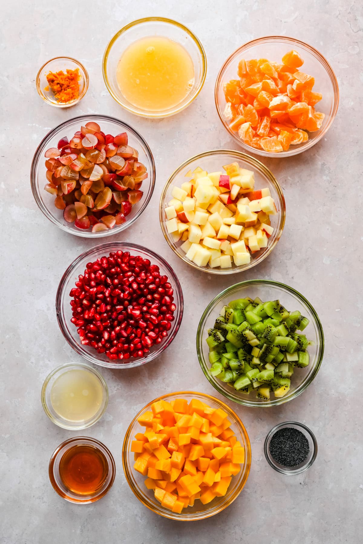 Overhead view of ingredients for winter fruit salad in small prep bowls. 